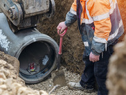 Groundworkers laying new concrete pipes during deep drainage work.
