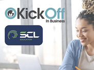 A mixed race woman working on a laptop if an office space, complete with Kick Off In Business SCL Education logos.
