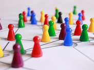 A network of multi-coloured ludo playing pieces on a white-lined surface.