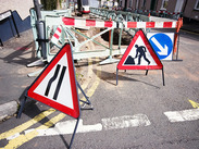 A residential road cordoned off with barriers and road work signs.