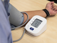 A blood pressure monitoring kit being used on a person's arm, showing hypertension with high systolic and diastolic readings.