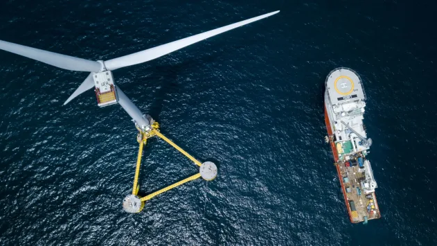 Arial view of a ship servicing an ocean wind turbine.