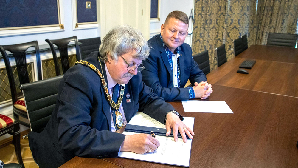 Chair of Somerset Council Mike Best signs the agreement with Ukraine, watched by the Ukraine Ambassador.