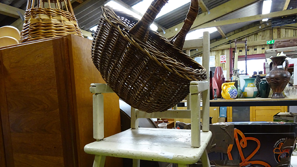 Interior view of Taunton Reuse Shop with used items on display, including furniture an a straw basket.