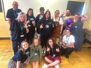 SiCC and SLCC staff with care leavers from the participation team posing indoors, some giving thumbs up and peace signs.