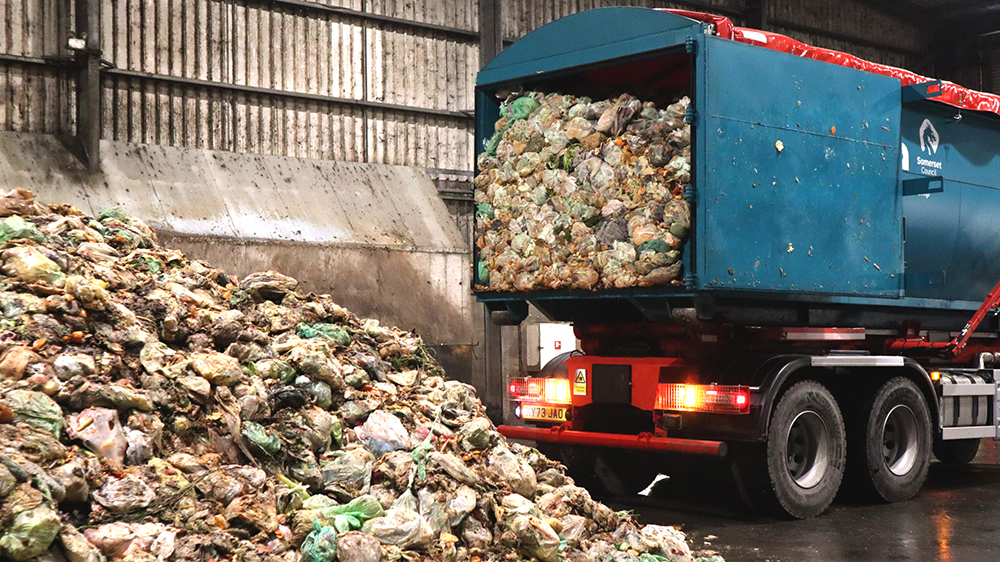 A lorry from Somerset Council unloads food waste for recycling at an indoor facility.