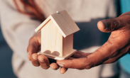 Hands holding wooden house