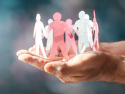 Paper chain depicting human figures are cupped in someone's hands.