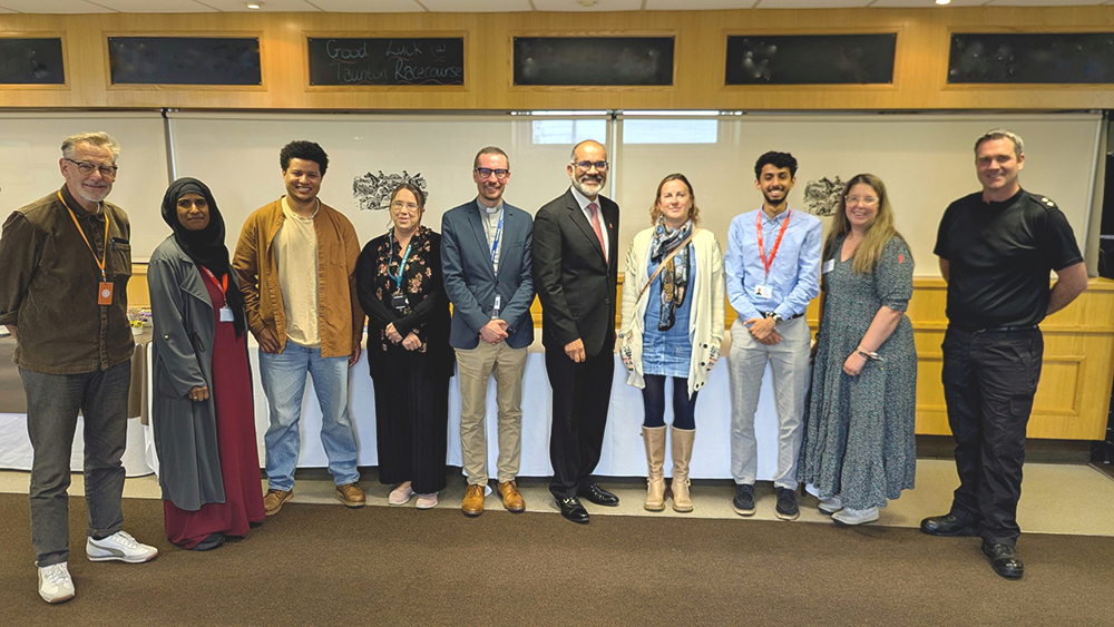 Diverse group of ten people stand together at a Hate Crime Awareness Week event, promoting unity and resilience.