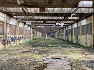 Interior of Saxonvale, an abandoned industrial building with graffiti, broken windows, and a deteriorated floor.