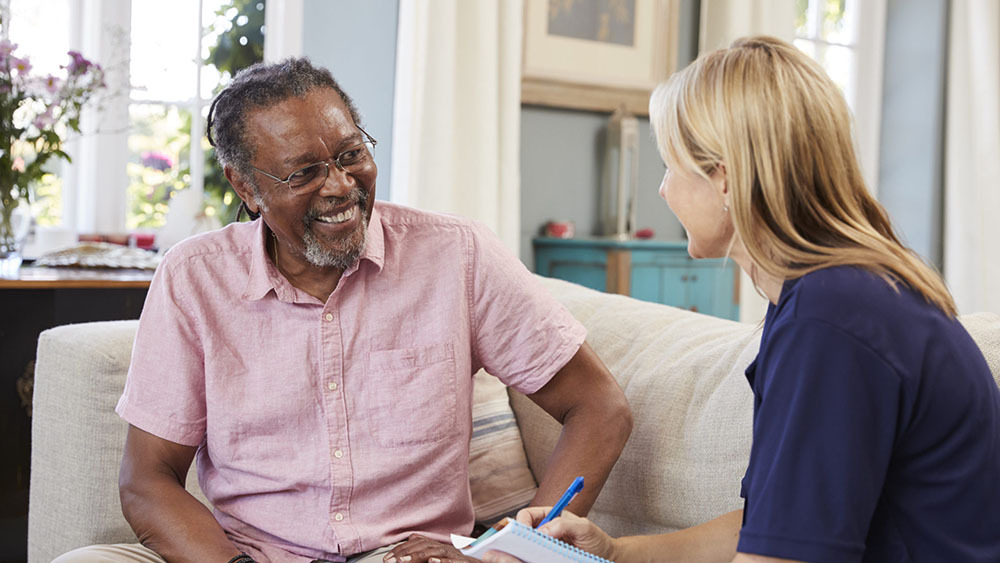 Female support worker visits senior man at home.
