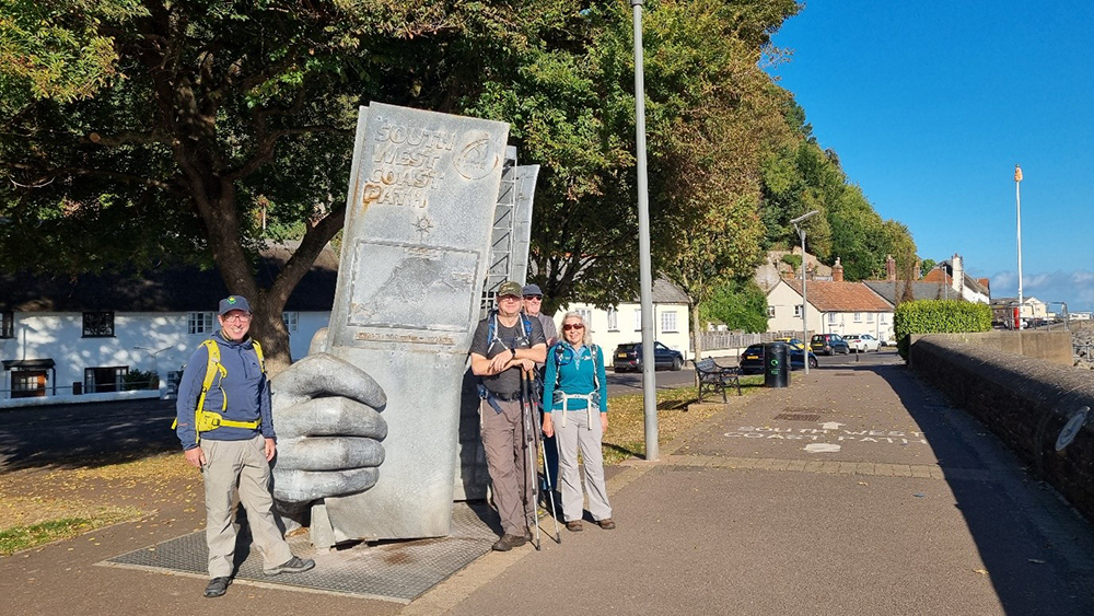 Walkers at the Trail Sculpture in Minehead, marking the end of the South West Coast Path section, by Isobel Pring.