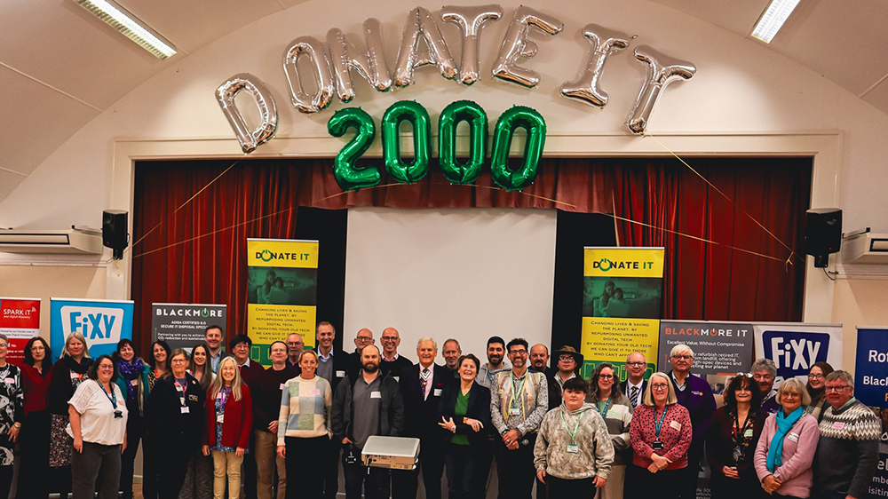 Group photo at Wincanton Memorial Hall under ‘Donate IT 2000’ balloons, marking 2,000th refurbished device milestone.