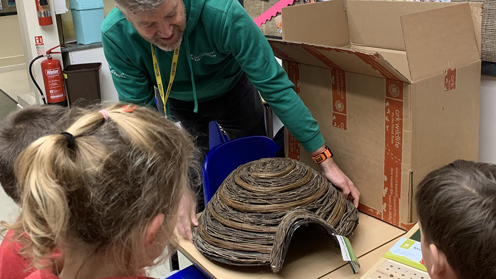 Children observe a hedgehog house and wildlife equipment being unpacked at Tintinhull School for Better Planet Schools award.