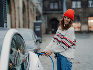 Woman plugging in a charging cable to an electric car.