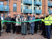 A ribbon-cutting ceremony marking the completion of new eco homes in Minehead, with officials gathered in front of the housing development.
