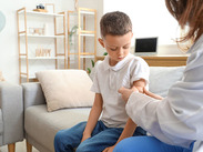 A child having a plaster applied to his arm after receiving a vaccination.