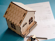 Picture of a wooden house and set of keys on top of a paper document.