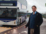 Councillor Richard Wilkins waiting at a bus stop for an approaching bus.