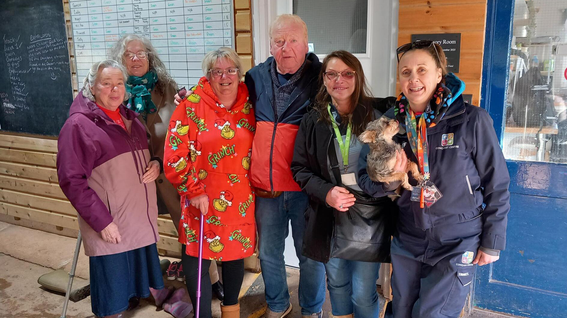Conquest Centre team standing together at the centre, marking a community wellbeing project with staff and a therapy dog.