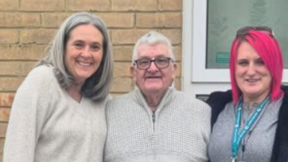 Tenant Jim standing outside his new home with housing and support staff, marking a positive new chapter after moving into sheltered accommodation.