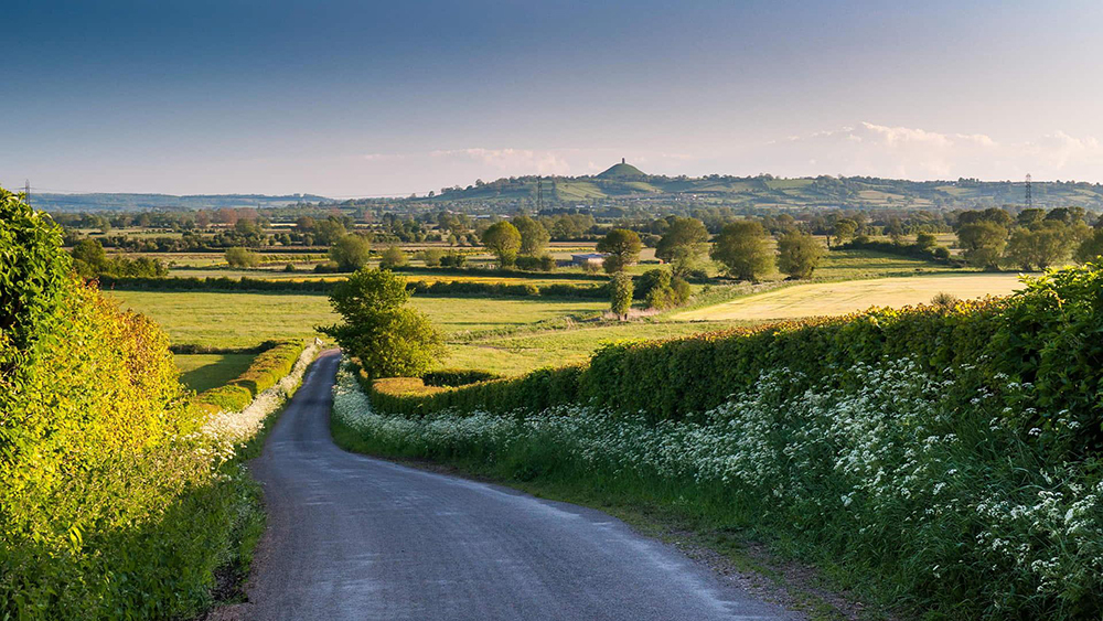 Photograph of a country road looking towards Glastonbury tor.