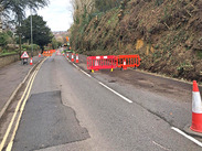 A30 Hendford Hill, Yeovil, after Storm Chandra, showing lane closure with cones and barriers beside a damaged roadside embankment.