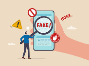 Illustration of a smartphone showing fake content, with a magnifying glass, warning symbols and hoax labels highlighting misinformation.