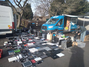 Unwanted laptops, tablets and phones laid out beside a Fixy van at a community venue, ready for reuse, refurbishment or recycling.