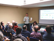 Attendees listen to a presentation at a Somerset Community Energy Network event, with slides highlighting local community energy projects.