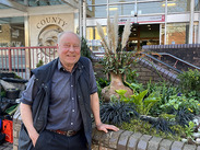 Brian Heath beside a planted community garden outside Taunton Library, showing diverse planting in a small walled green space.