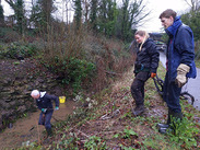 Volunteers clearing vegetation at the Shepton Mallet Cutting Local Geological Site to reveal exposed Jurassic rock layers.
