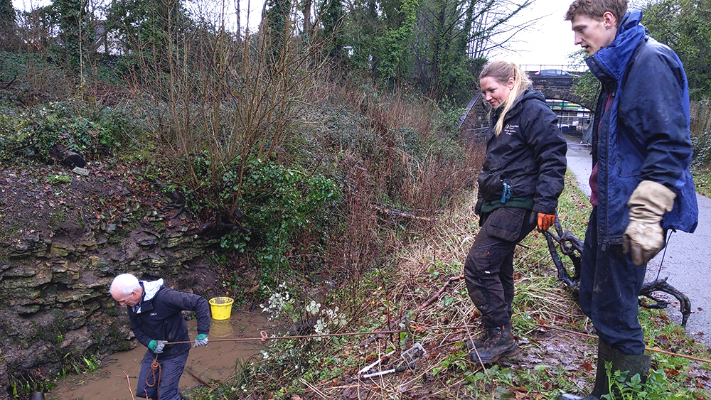 Volunteers clearing vegetation at the Shepton Mallet Cutting Local Geological Site to reveal exposed Jurassic rock layers.