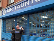 Trading Standards officers secure a closed Taunton convenience store, fixing a closure notice to the shuttered frontage.