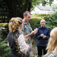 Group takes part in a ranger-led outdoor session on Exmoor, discussing nature and wildlife tourism ideas in a wooded landscape.