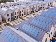 Aerial view of a new housing development with rows of brick homes, each fitted with solar panels on their roofs.