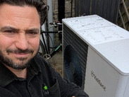 Frome homeowner Matt beside his newly installed air source heat pump, giving a thumbs up outside his home.