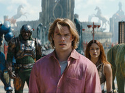 Characters from Masters of the Universe walk through a fantasy city set, including armoured figures and a large green tiger.