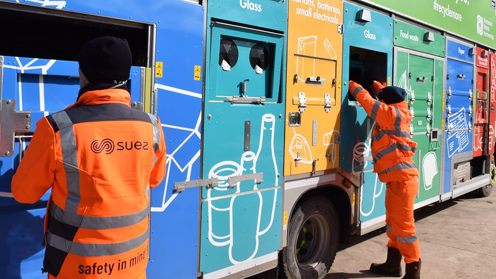 Recycling crews loading a lorry, placing materials into colour-coded compartments for glass, paper and mixed recycling.