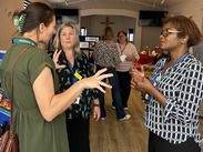 Somerset Council staff with lanyards talk at a community information event, with display boards and attendees in the background.