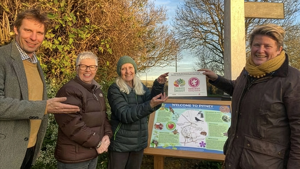 Cllr Wilkins (L) and Sarah Dyke MP (R), MP for Glastonbury and Somerton, with Pitney Biodiversity Working Group members by village sign.