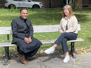 Abdul sits with a Somerset Council Displaced People Service staff member on a park bench during Refugee Week campaign.