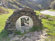 Boundary marker with new brushed steel Mendip Hills National Landscape sign set into drystone wall.