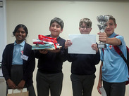 Four pupils from St George’s Catholic Primary School hold a trophy, certificate and prizes after children’s parliament event.