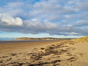 Brean Sands beach with dunes and wide shoreline under dramatic skies on the Somerset coast.