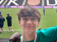 Lewis, wearing a Somerset Council football shirt and medal, stands pitchside at MK Dons Stadium after the national tournament.