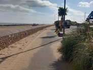 Sand being returned to Minehead beach, with tractors and machinery working along the seafront beside the promenade.