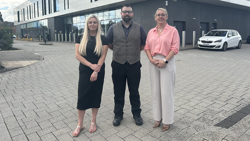 Natalie Mears with 2 other partner organisation representatives stand outside A&S Police HQ supporting domestic abuse awareness.