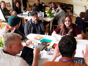 Participants collaborate around tables during a creative technology workshop, discussing ideas and AI innovation projects.