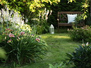 Wooden bench beside a planted garden path with blooming daylilies in summer.